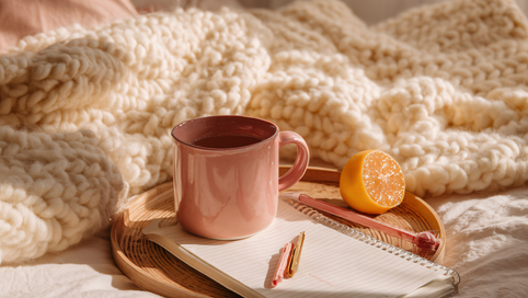 Warme avondroutine met een kop thee, magnesiumsupplement en kaarslicht op een nachtkastje voor rust en diepe slaap.