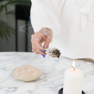 Rustige setting met kaars en witte salie voor een beschermend huisritueel