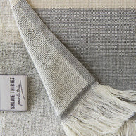 detail van grijs gestreept strandlaken met franjes
