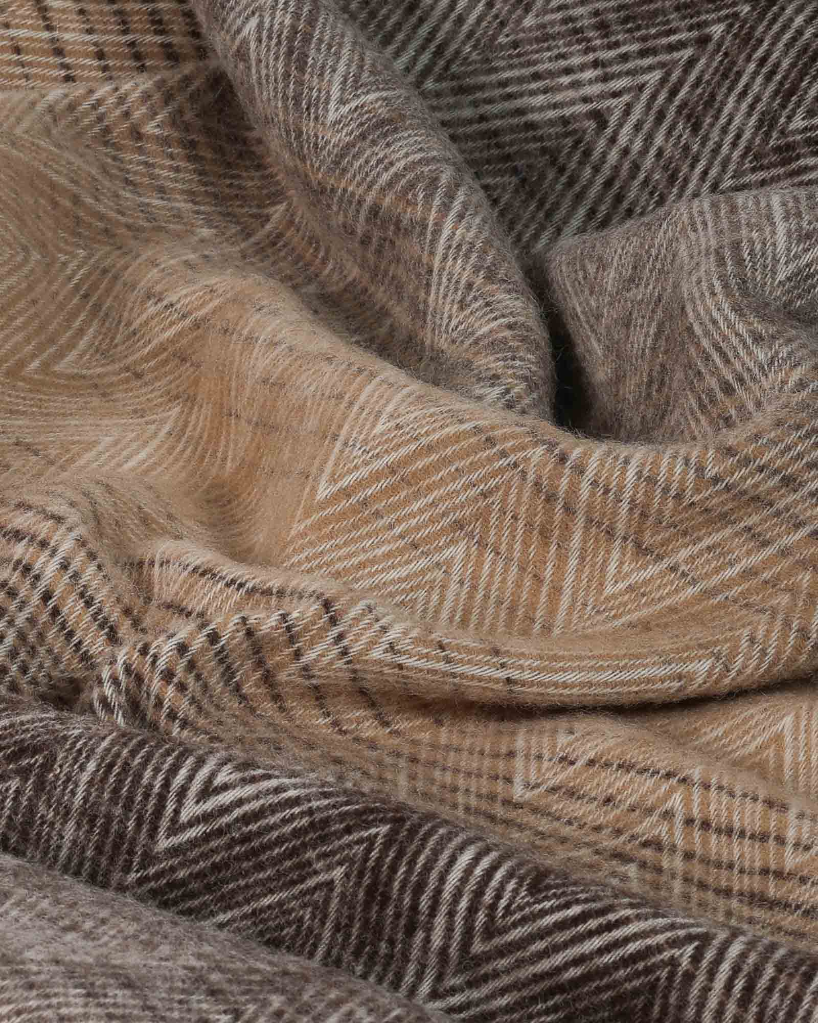 Detail van het zigzagpatroon en de natuurlijke kleurtinten van de wollen plaid