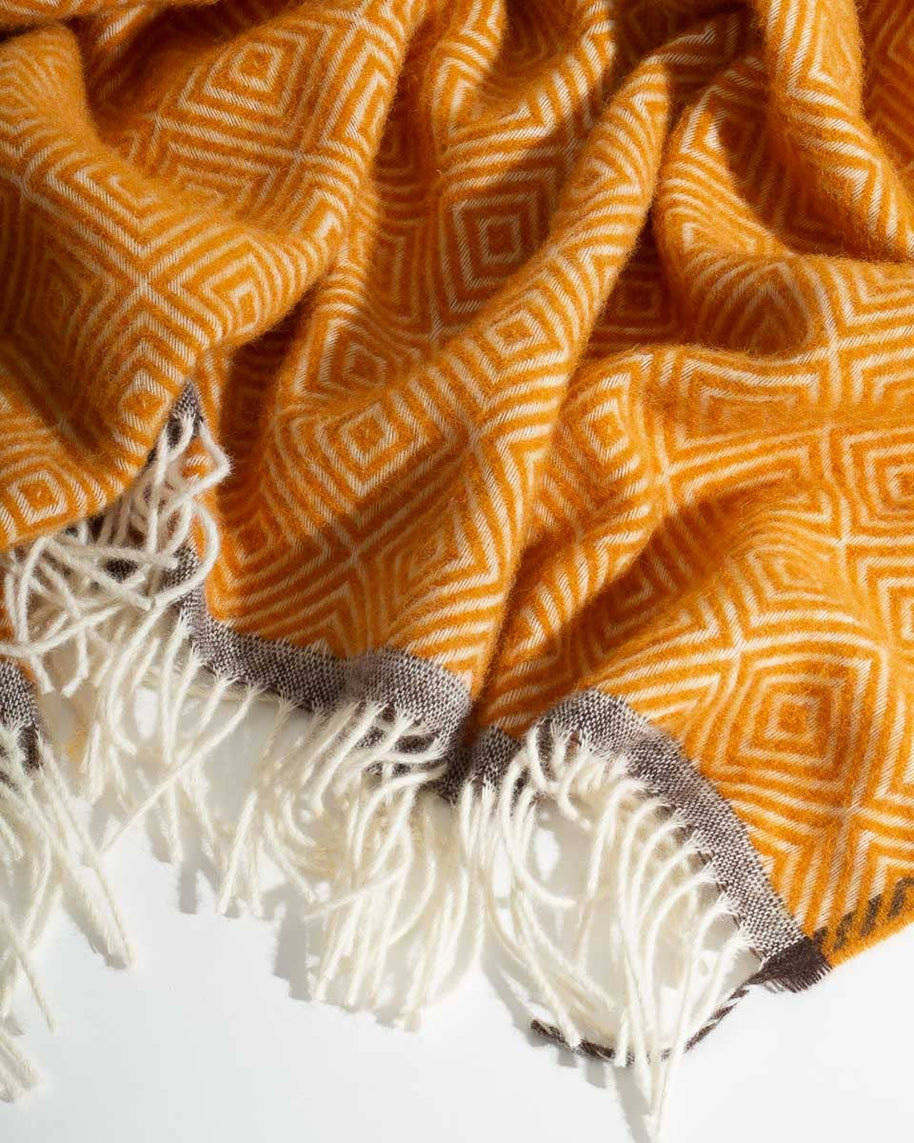 Detail van een warmgele wollen deken met zachte franjes