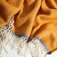 Detail van een warmgele wollen deken met zachte franjes