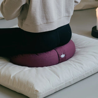 Halvemaan meditatiekussen gebruikt tijdens meditatie in rustige ruimte