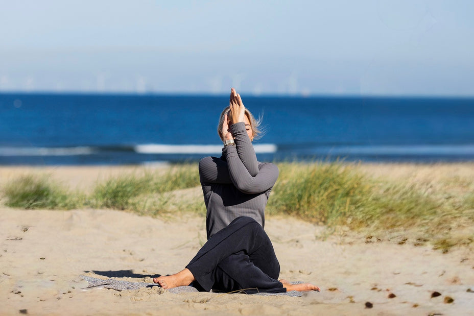 Yin yoga houding op het strand, rustige zittende stretch met aandacht voor ademhaling en ontspanning.