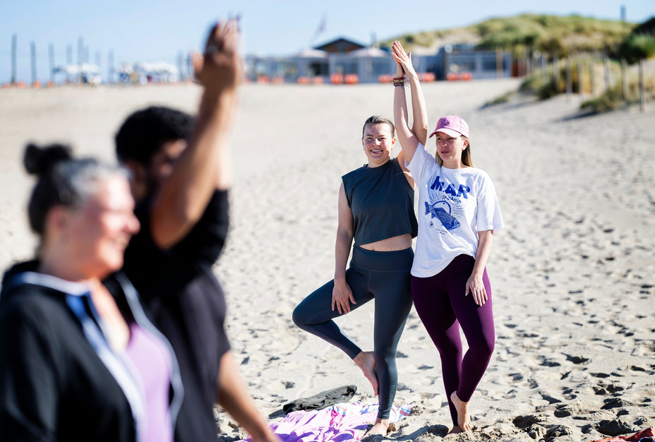 Yoga workshop voor groepen op het strand, gezamenlijke yogales met ruimte voor ontspanning en plezier.