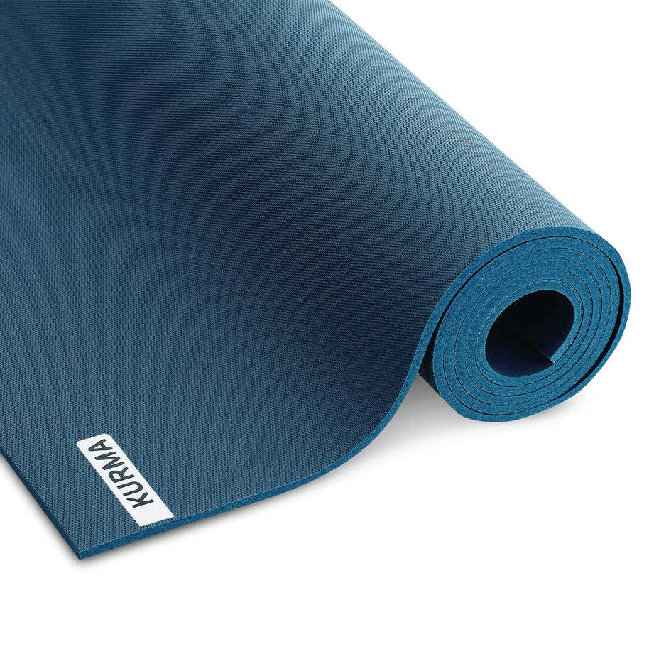 Een antracietgrijze CORE yogamat verticaal opgerold, staand in een minimalistisch interieur, klaar voor een moment van rust en yoga.