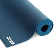 Een antracietgrijze CORE yogamat verticaal opgerold, staand in een minimalistisch interieur, klaar voor een moment van rust en yoga.