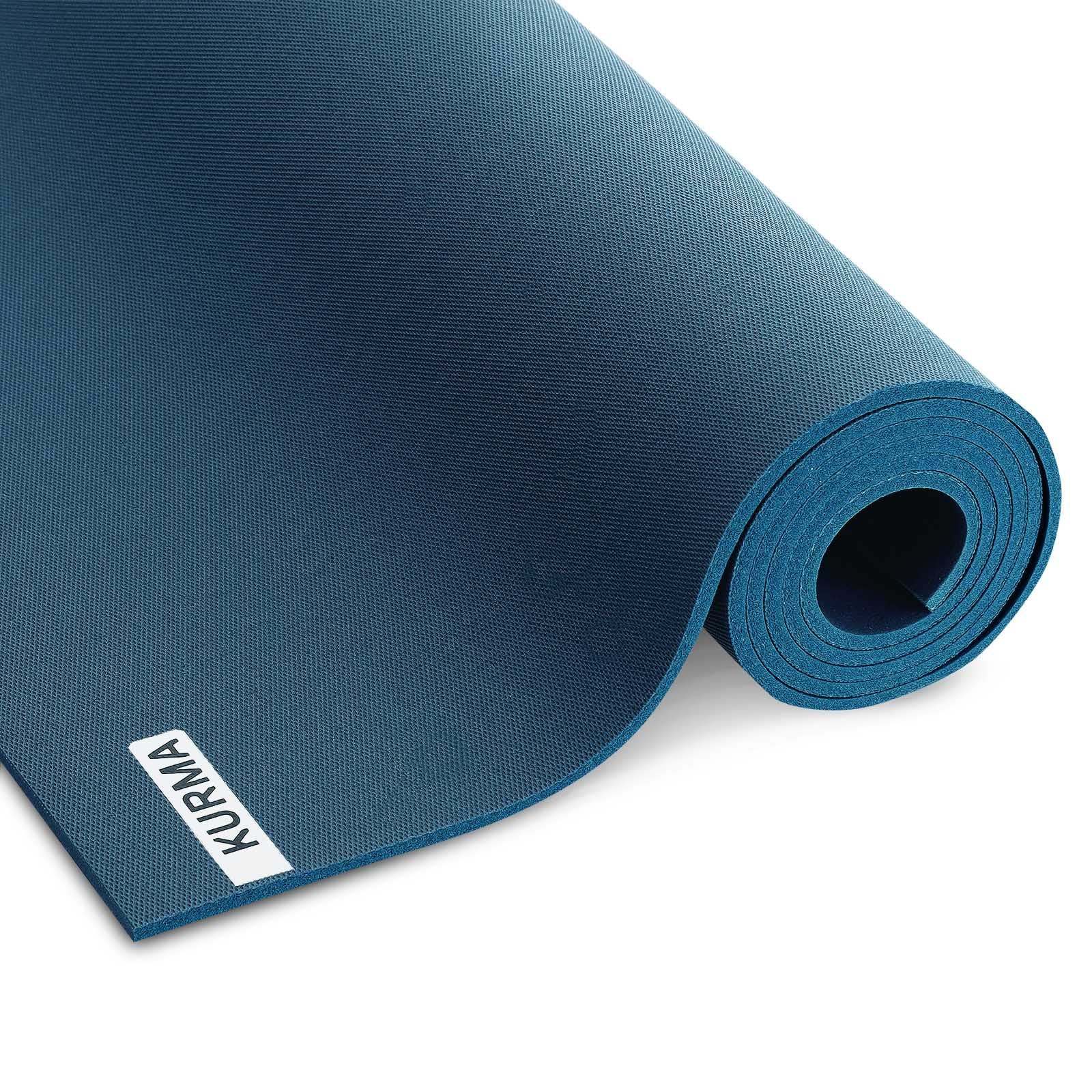 Een antracietgrijze CORE yogamat verticaal opgerold, staand in een minimalistisch interieur, klaar voor een moment van rust en yoga.