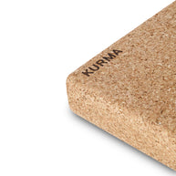 Close-up van de hoek van het kurkblok met het ingegraveerde KURMA-logo en de fijnkorrelige, natuurlijke textuur.