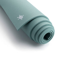 Een zachtgroene CORE yogamat, strak opgerold met het KURMA  logo subtiel zichtbaar voor een natuurlijke uitstraling.