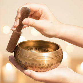 Messing klankschaal in handen met houten klopper tijdens meditatie
