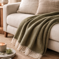Olijfgroene wollen plaid op bank voor warmte, rust en een tijdloos interieur