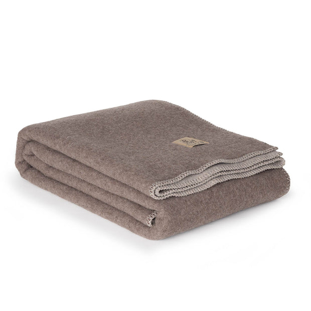 Opgevouwen merinowollen deken in bruin en beige met rustige, volle wolstructuur