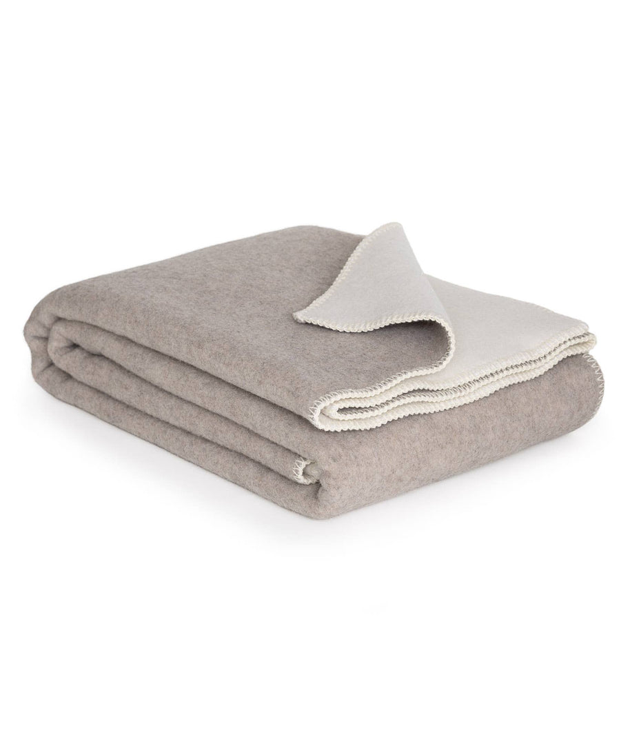 Opgevouwen merinowollen deken in wit en beige met zachte afwerking
