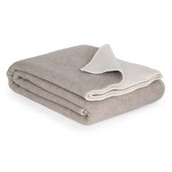 Opgevouwen merinowollen deken in wit en beige met zachte afwerking