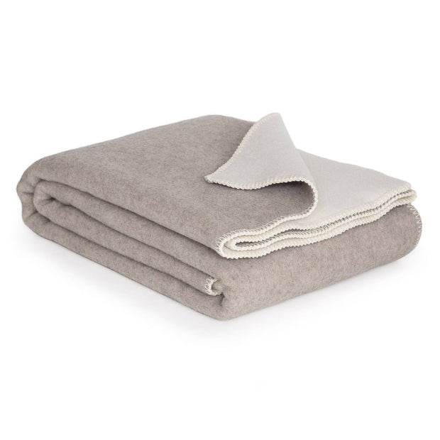 Opgevouwen merinowollen deken in wit en beige met zachte afwerking