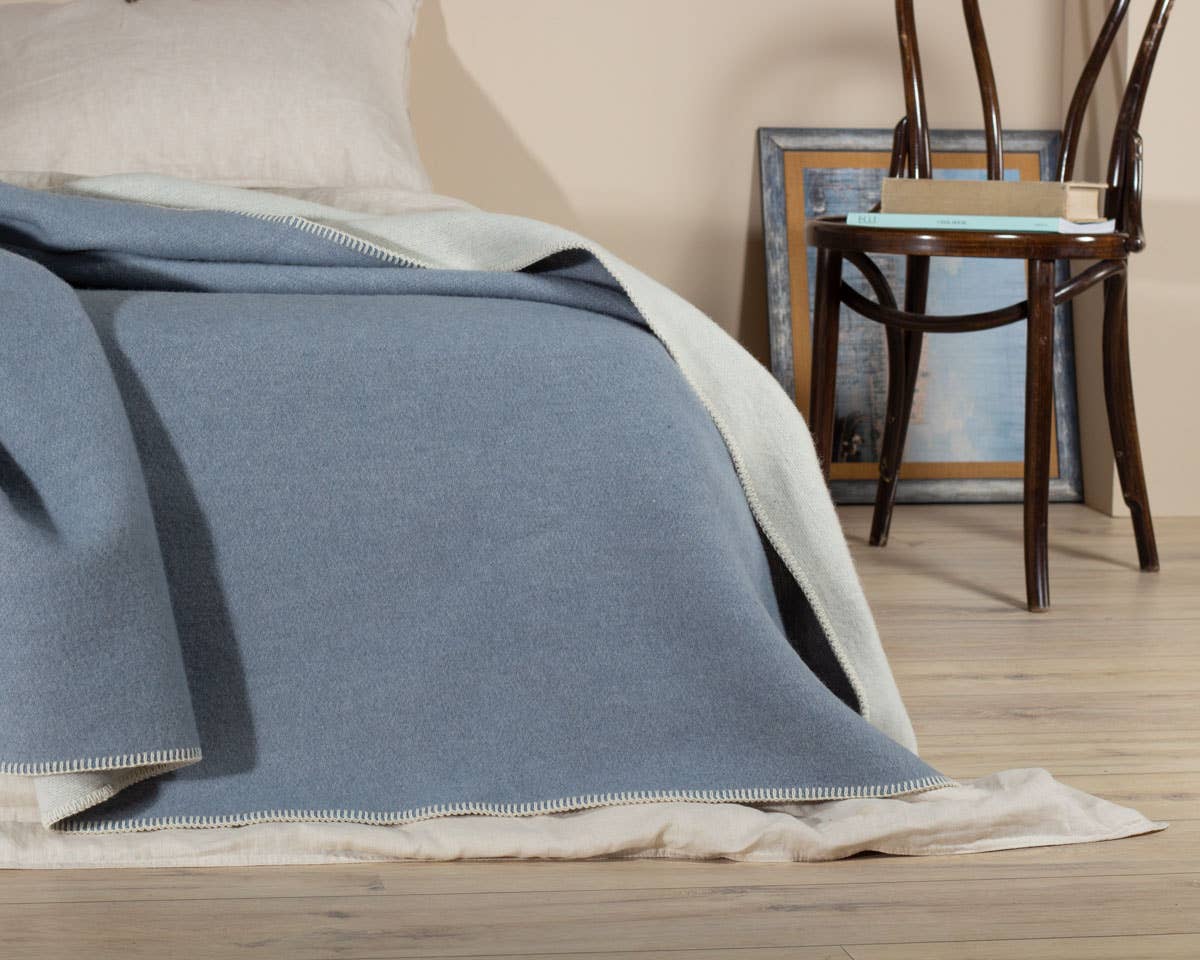 Wollen deken BLUE FOG gebruikt als extra laag in een lichte, serene ruimte