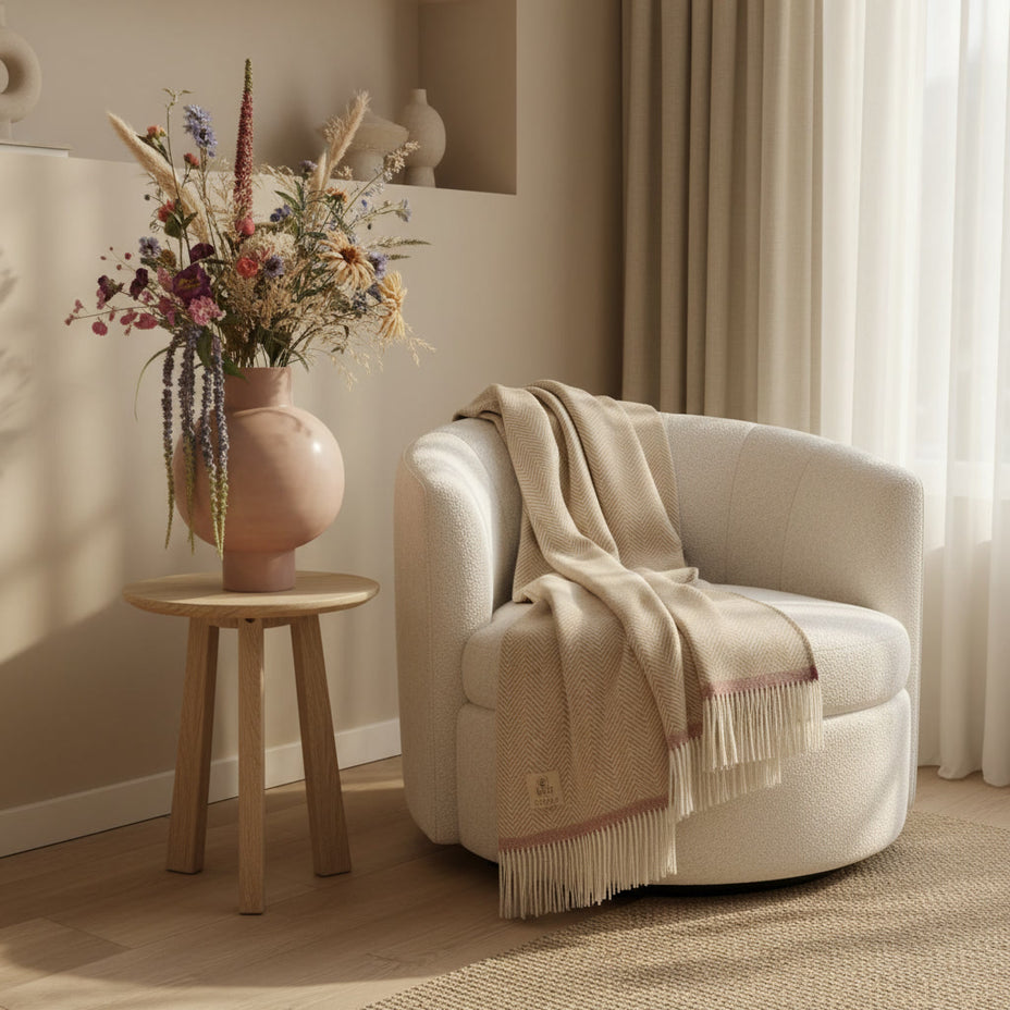 Zachte crème wollen plaid met zigzagpatroon gedrapeerd over fauteuil in warm interieur