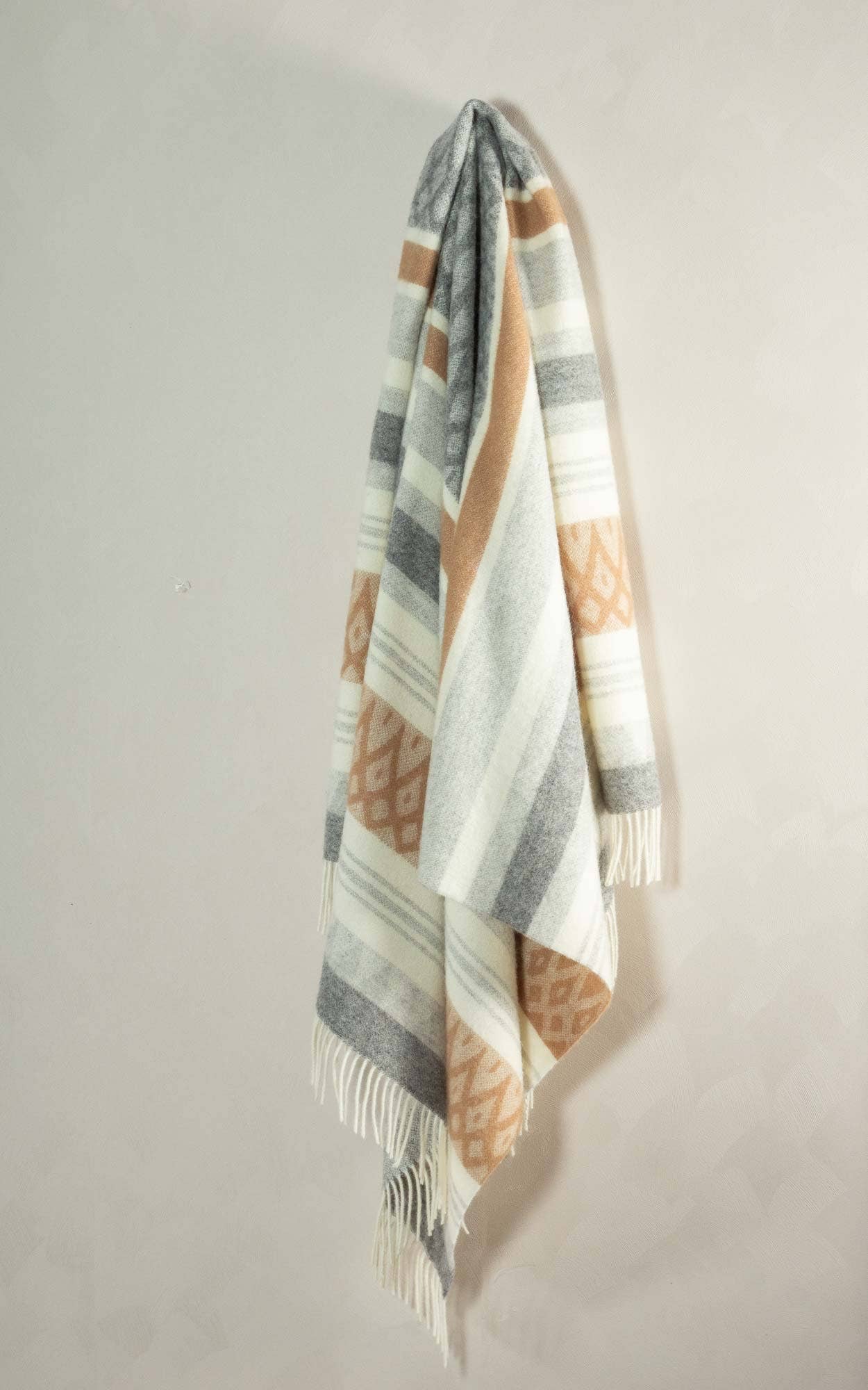 Wollen plaid van Nieuw-Zeelandse wol hangend aan de muur met zachte, natuurlijke kleuren
