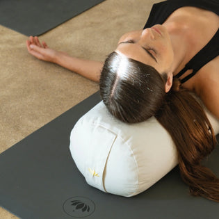 vrouw gebruikt yogabolster tijdens yin yoga op yogamat