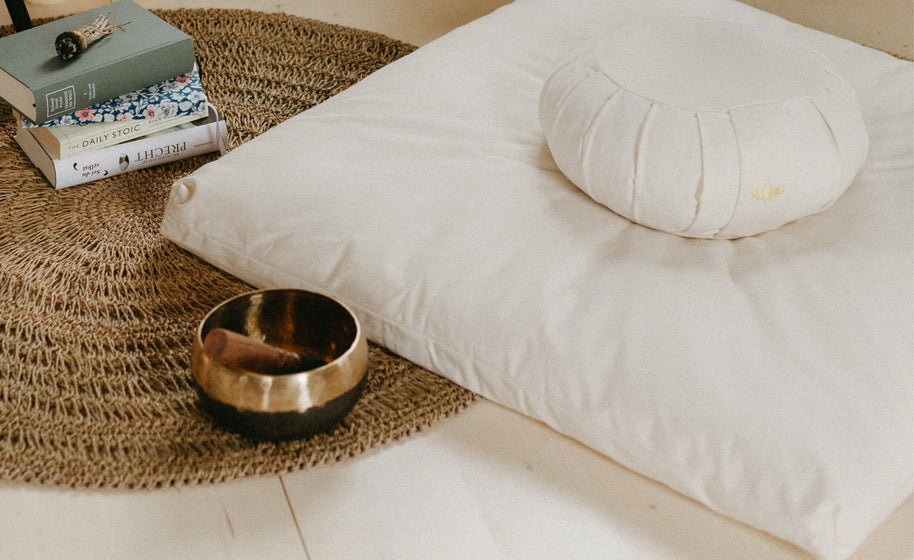 Zafu meditatiekussen op bed naast klankschaal