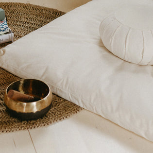 Zafu meditatiekussen op bed naast klankschaal