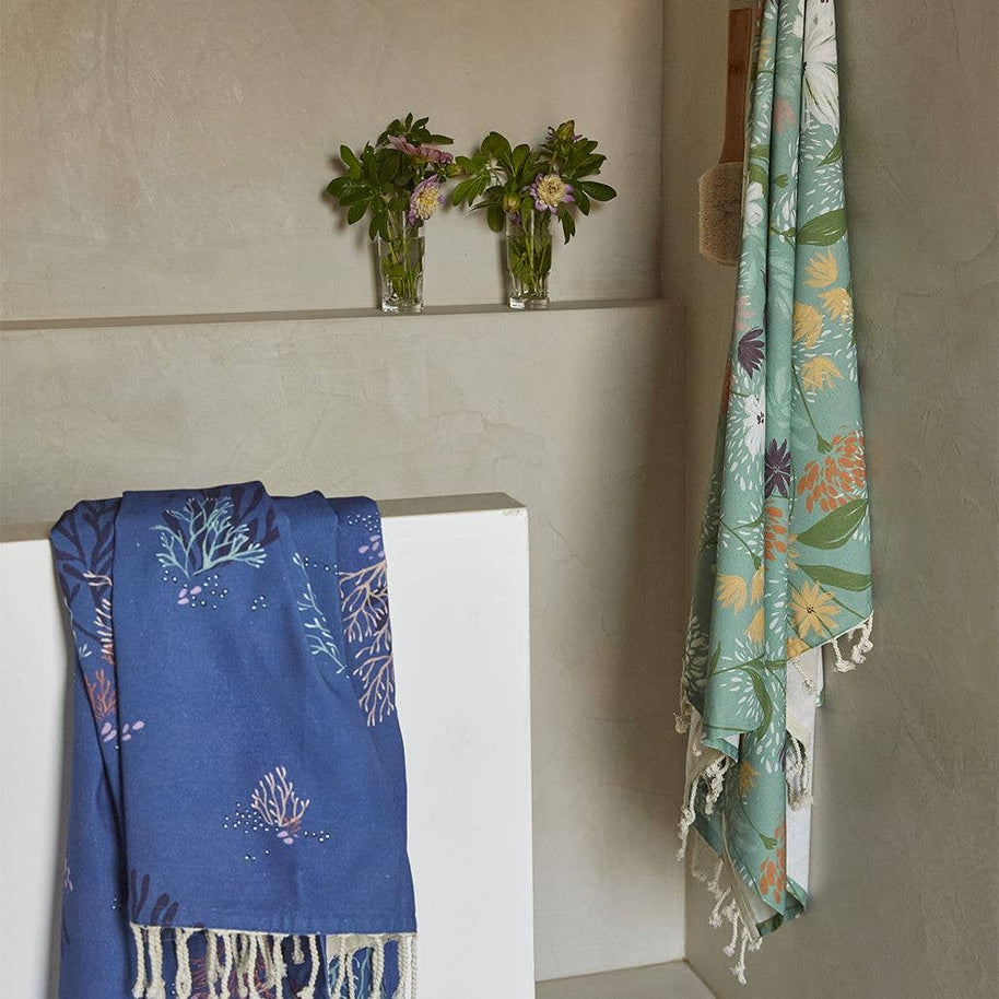 blauwe fouta strandlaken met oceaanmotief opgehangen aan muur