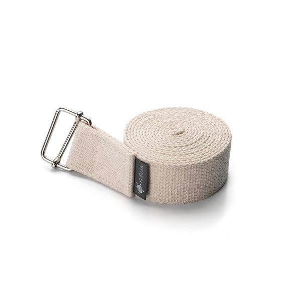 Detailopname van de zilverkleurige metalen gesp en creme witte riem van de Kurma yogariem die slippen voorkomt tijdens stretches.