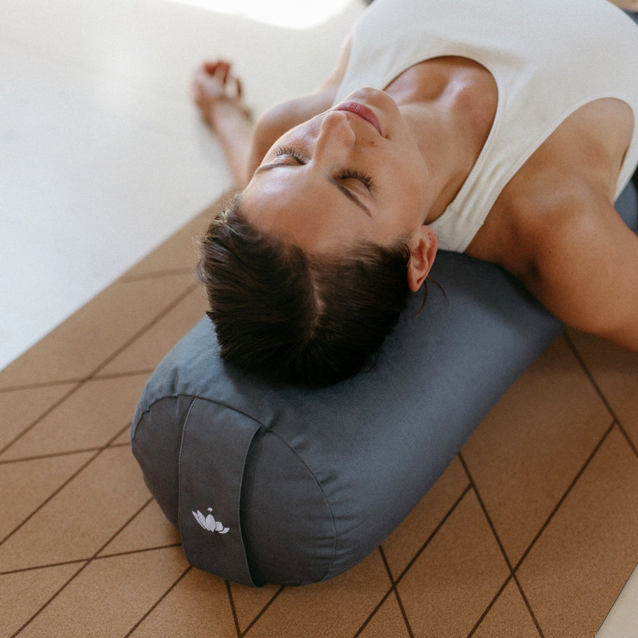 vrouw ontspant op yogabolster tijdens savasana
