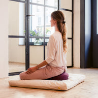 Yogi zit op laag meditatiekussen tijdens meditatiemoment