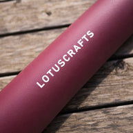 Detail van roze Arise Yogamat op houten ondergrond aubergine wijn rood