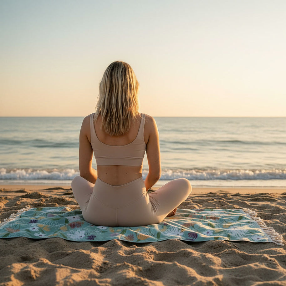 vrouw mediteert op strandlaken op het strand bij zonsondergang